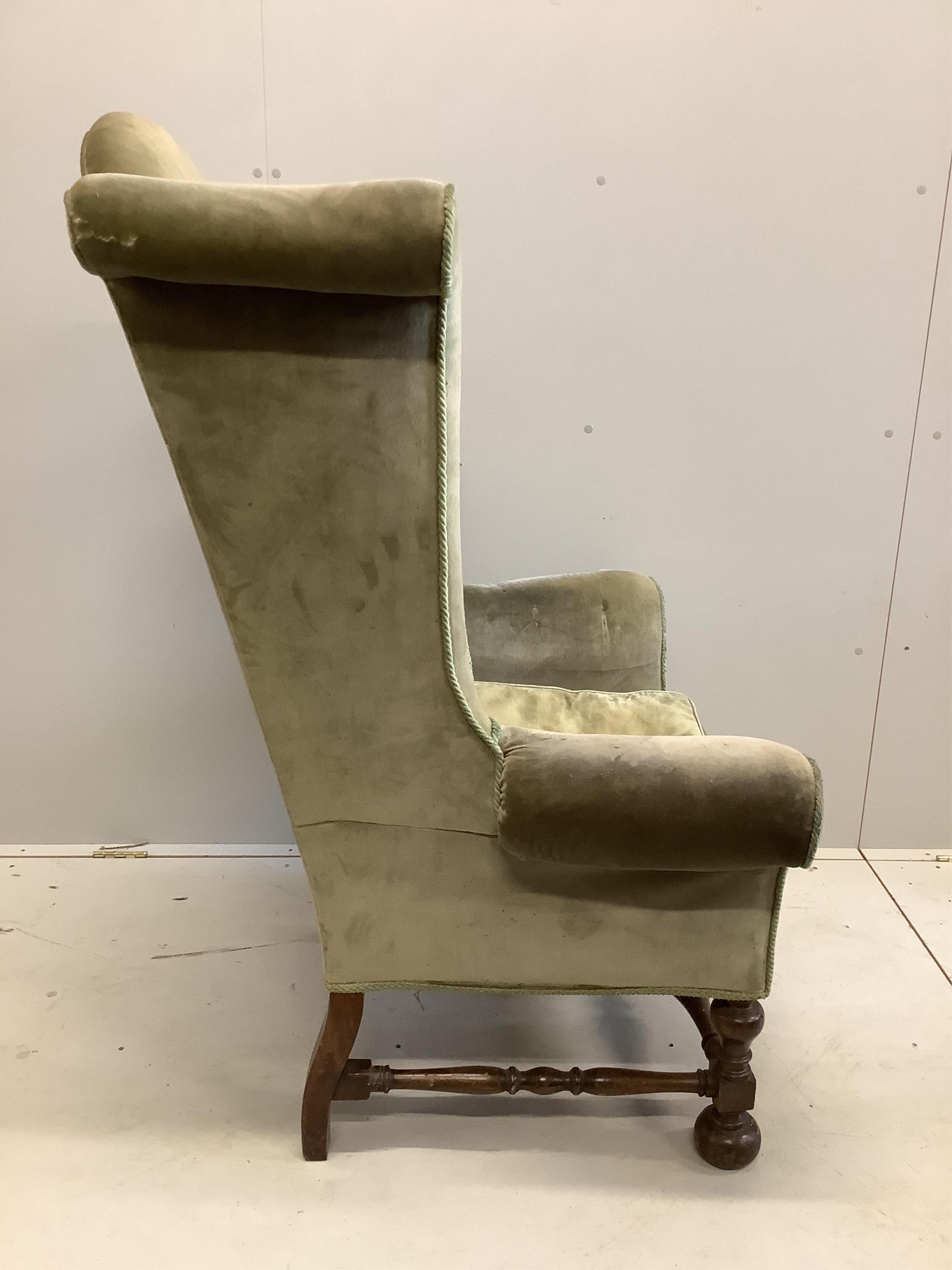 A William and Mary style wing back armchair, upholstered in green dralon, width 68cm, height 136cm. Condition - poor